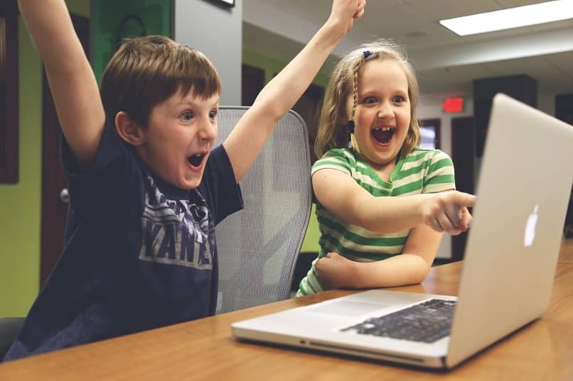 niños felices usando laptop