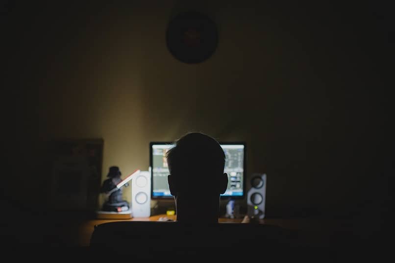 hombre mirando la luz del monitor en una habitación oscura