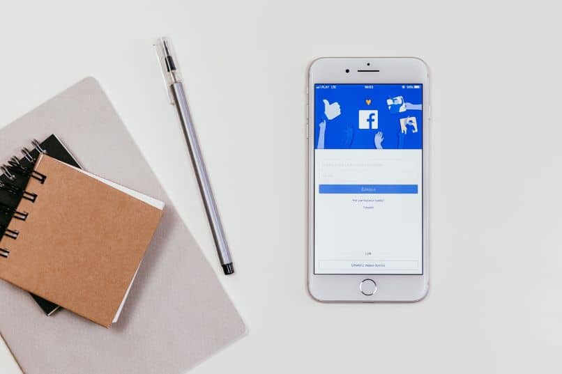 smartphone con aplicación de facebook y cuadernos